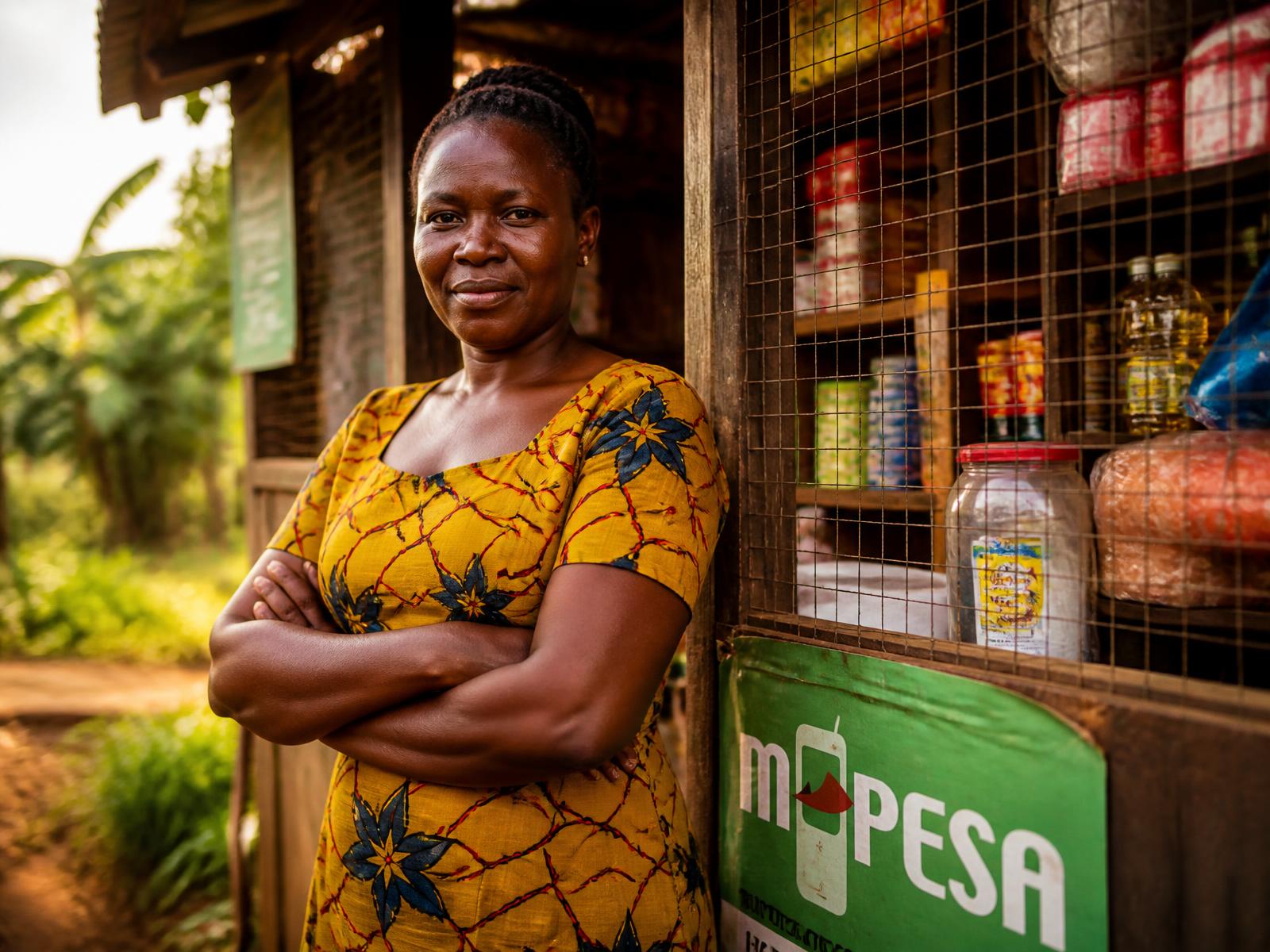 A Kenyan shop owner standing outside her stocked roadside kiosk